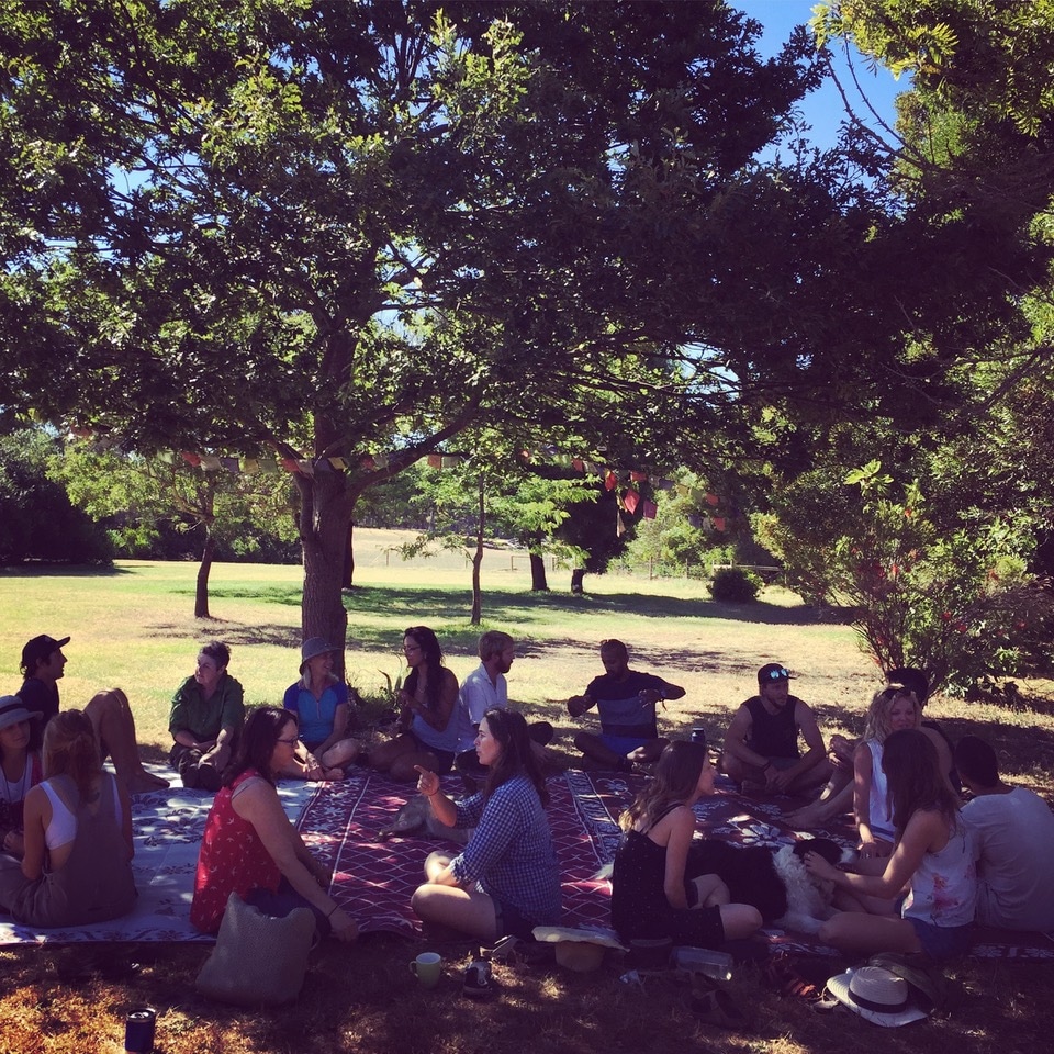 Photograph of students sitting together under an oak tree.